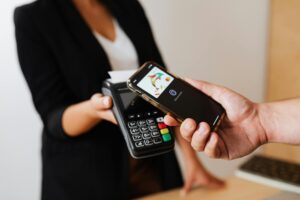 How iPhone Users Are Replacing Banking Apps with Apple Wallet Person using smartphone for contactless payment at retail terminal