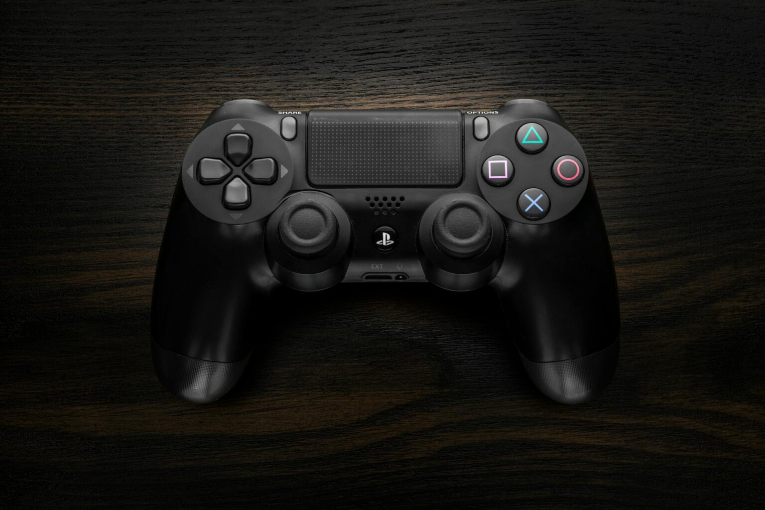 Close-up of a gaming controller on a dark surface showing buttons and analog sticks