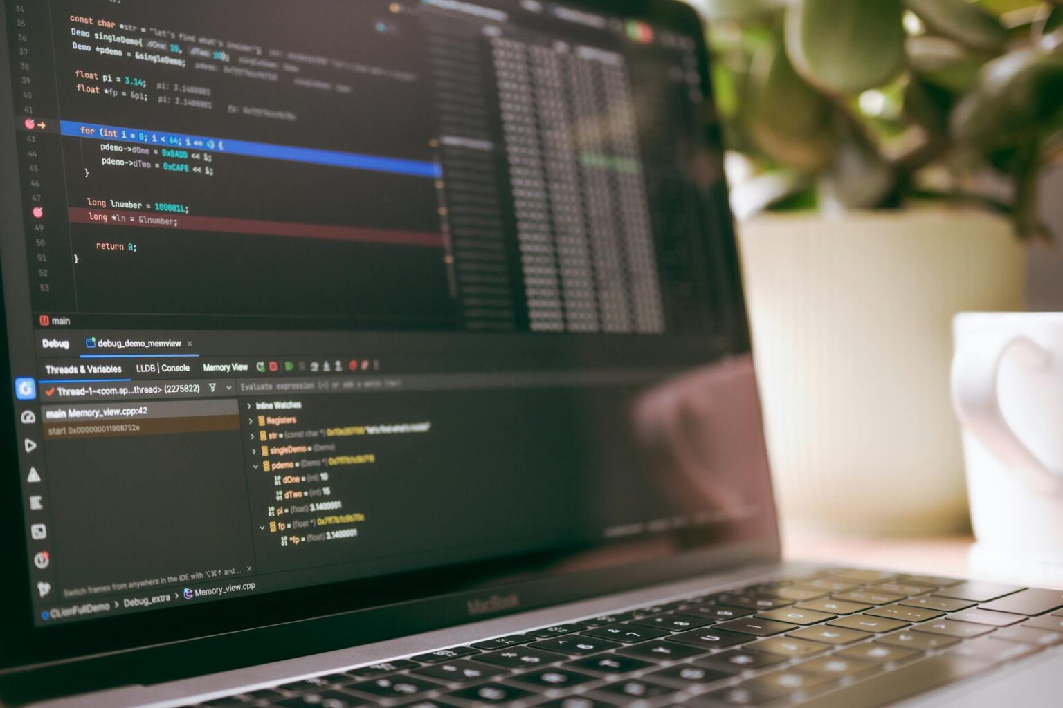 Developer working on laptop with code editor displaying programming interface