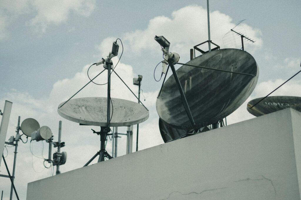 Why Satellite Emergency SOS Features Are Expanding Beyond Apple and iPhone Large satellite communication dish against blue sky representing satellite technology infrastructure