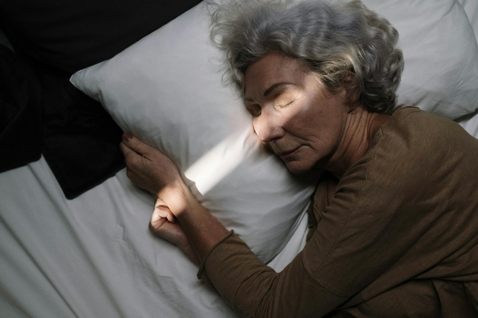 Person sleeping peacefully in bed wearing minimal sleep monitoring device