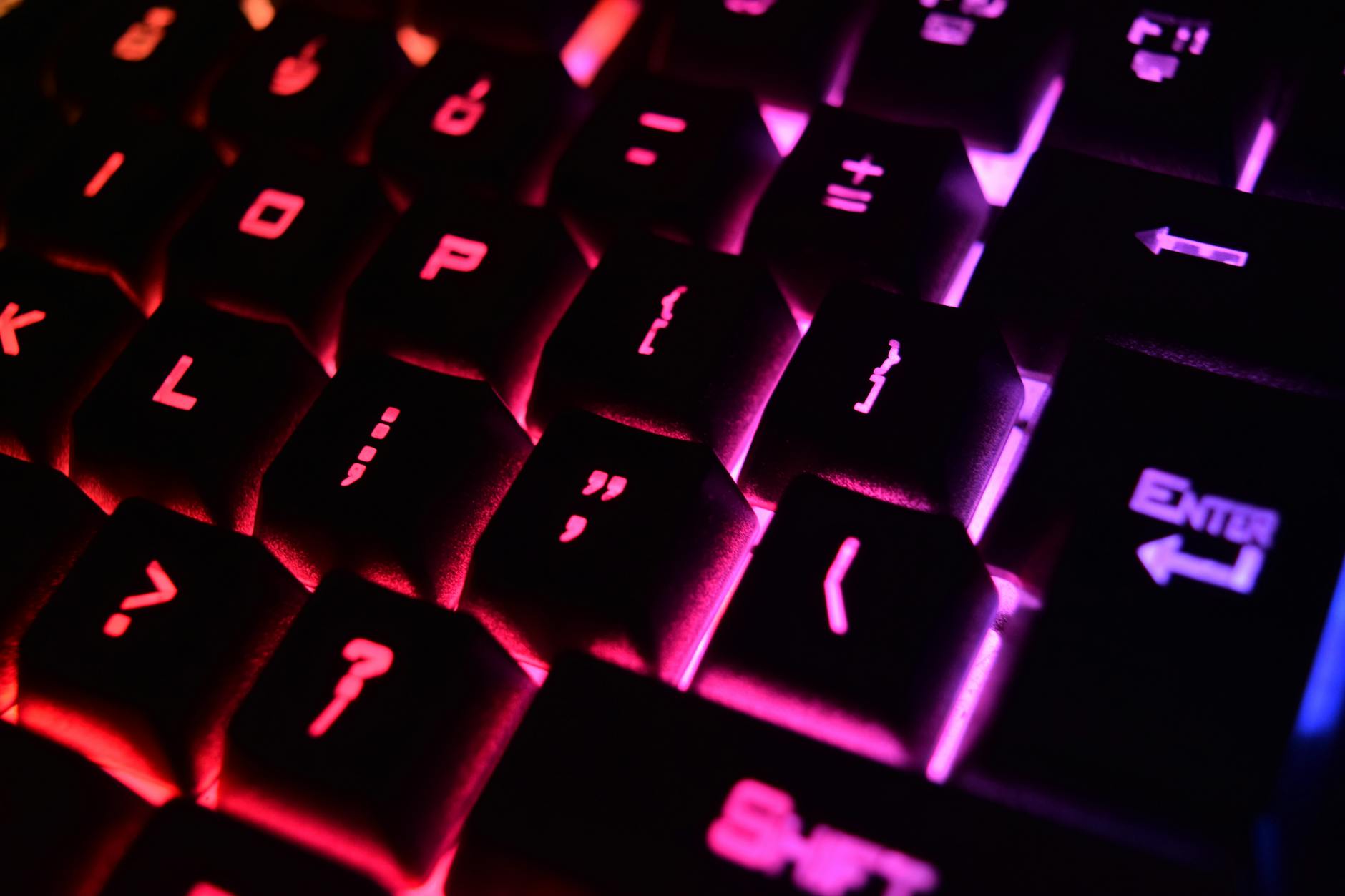 Backlit gaming keyboard on a desk showing RGB lighting effects