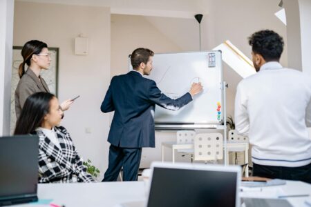 Microsoft Teams Is Losing Enterprise Customers to Zoom’s New Whiteboarding Features Business professionals collaborating around a digital whiteboard during a team meeting