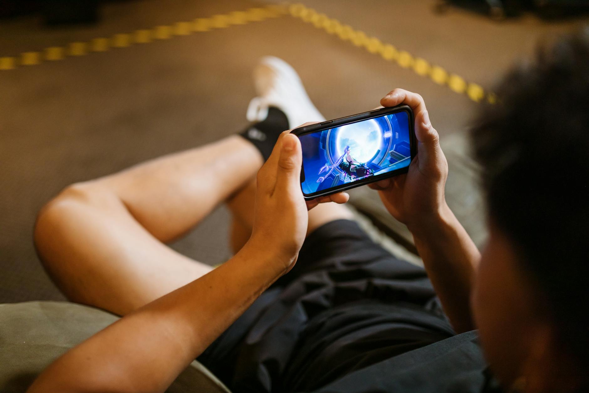 Person holding a phone with a gaming controller grip while playing a mobile game