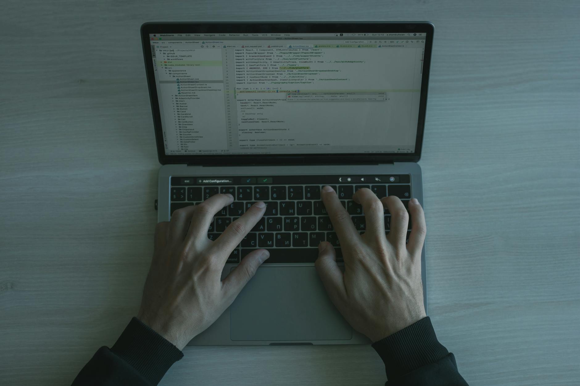 Software developer's hands typing on mechanical keyboard with code editor visible on screen