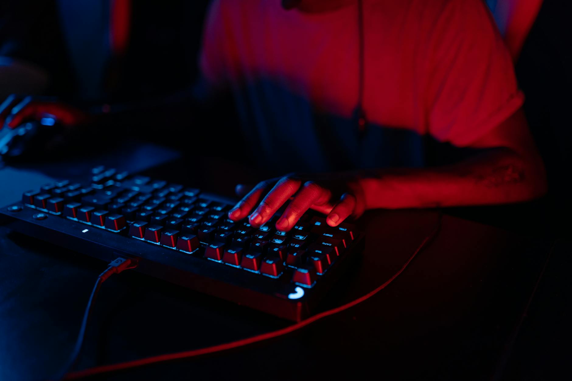 A person playing a video game at night, lit by monitor light in a dark room