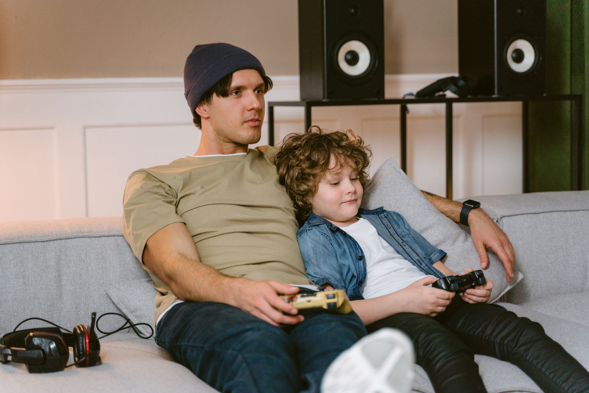 Parent and child playing video games together on a couch