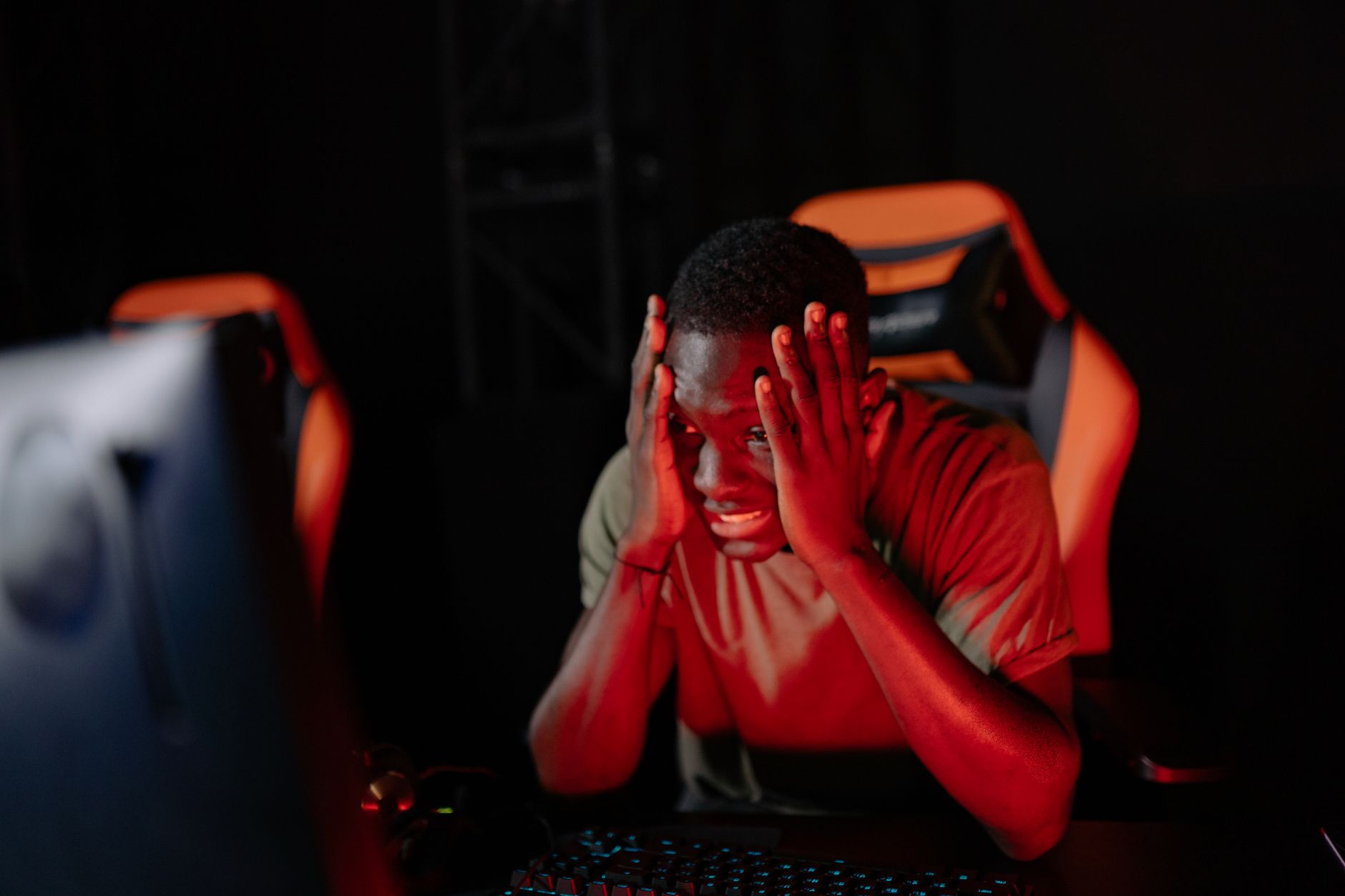 A person sitting at a gaming desk showing signs of frustration