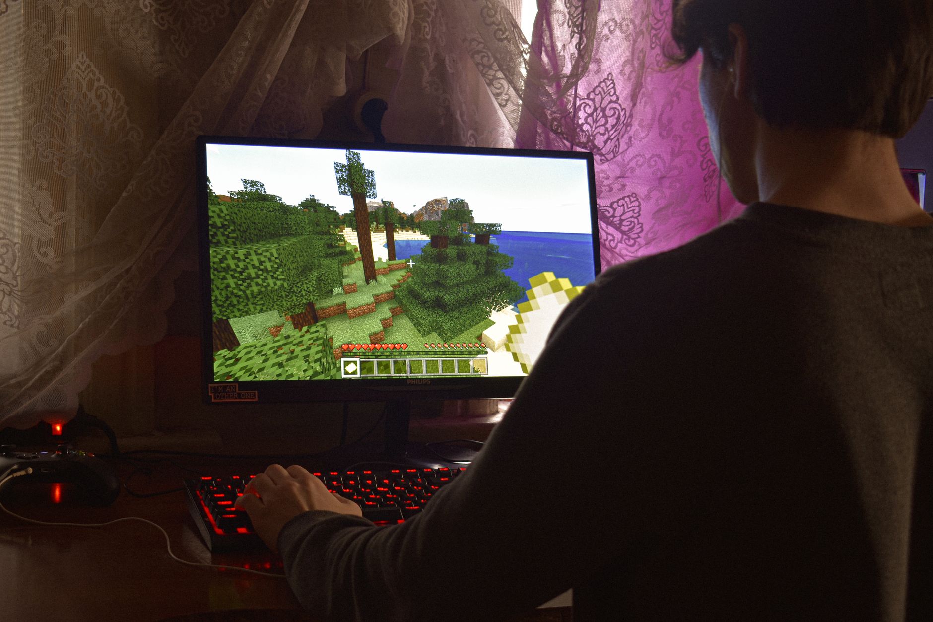 A person playing a video game on a large monitor in a dark room