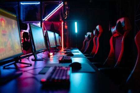 A dark gaming setup with monitors glowing in a dimly lit room, representing intense PC gaming sessions
