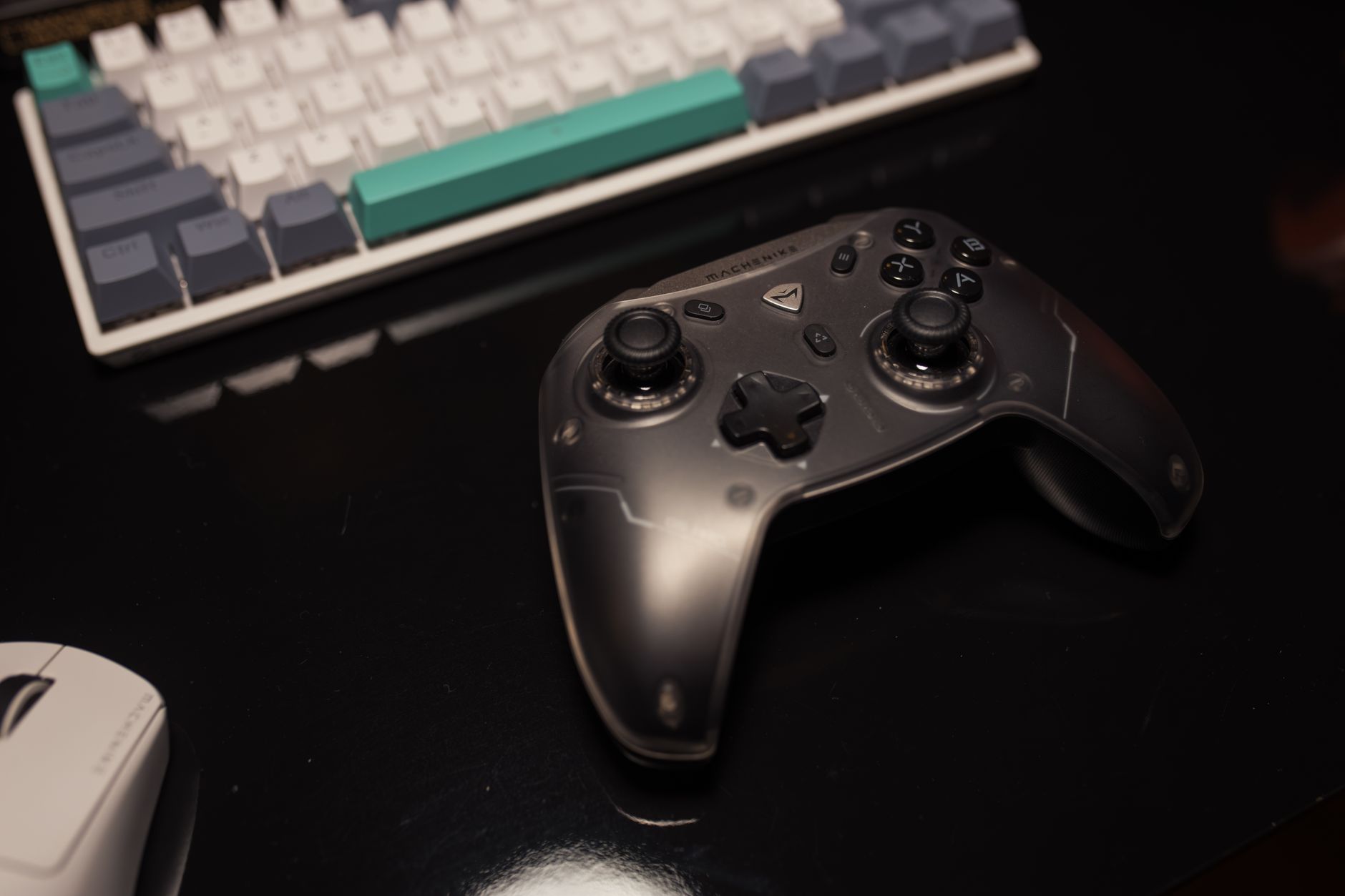 A gaming controller resting on a desk beside a monitor displaying a dark game environment
