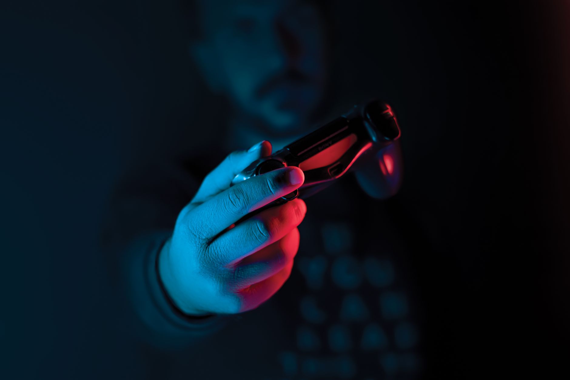 A person holding a game controller in a darkened room, symbolizing late-night gaming sessions revisiting classic titles