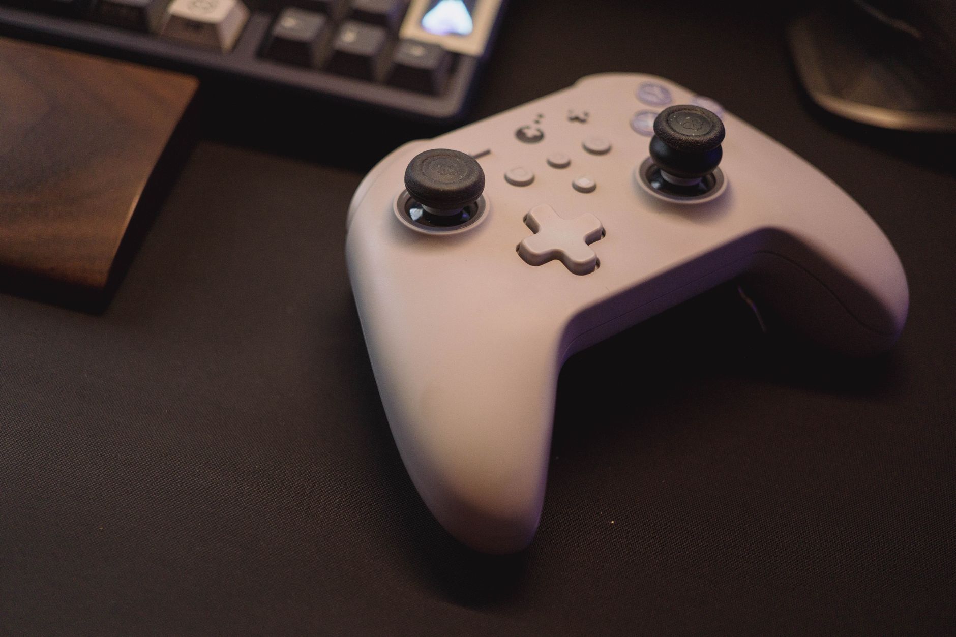 A gaming controller resting on a desk next to a PC setup
