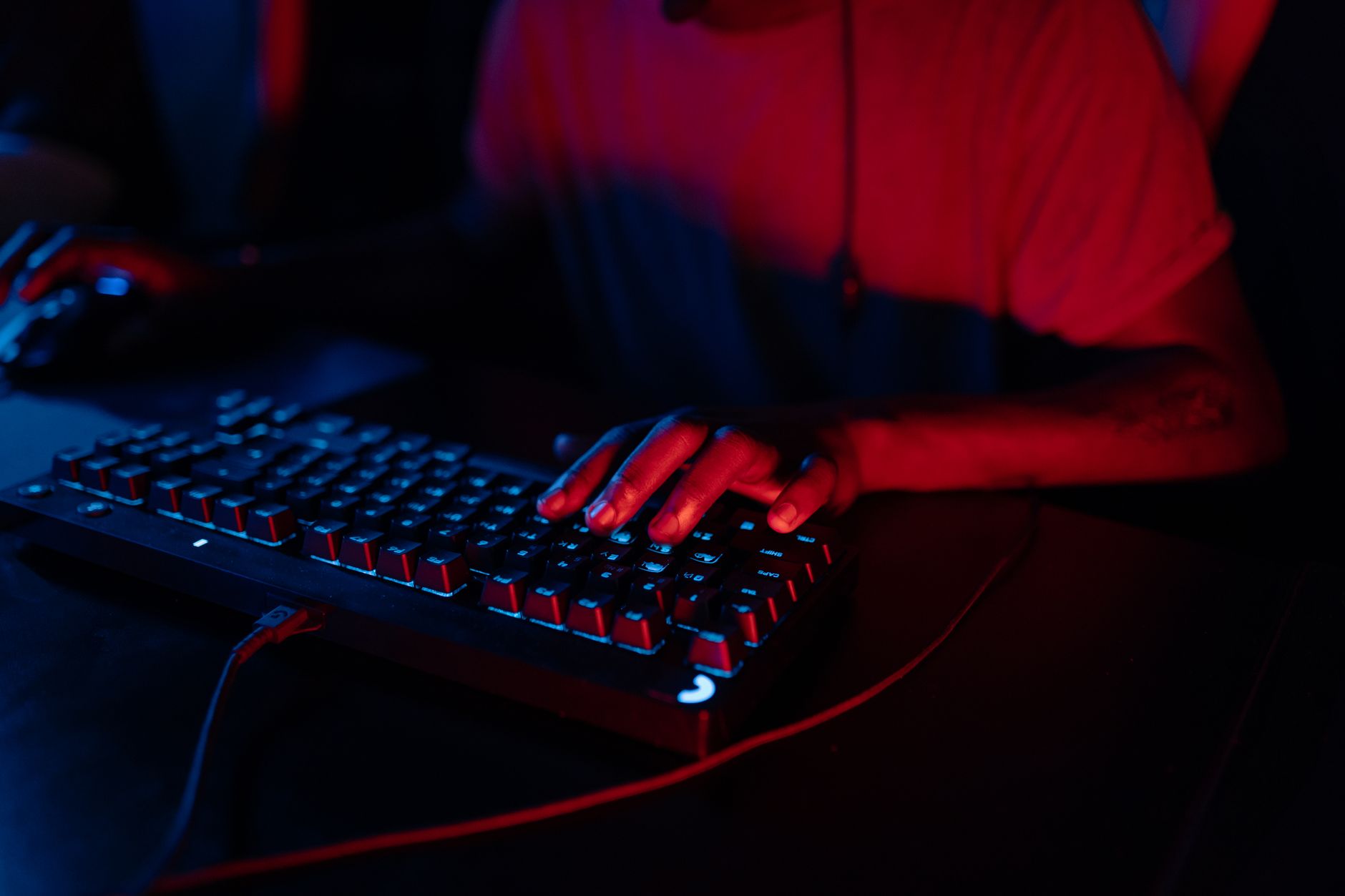 Person playing a video game in a darkened room lit by monitor glow
