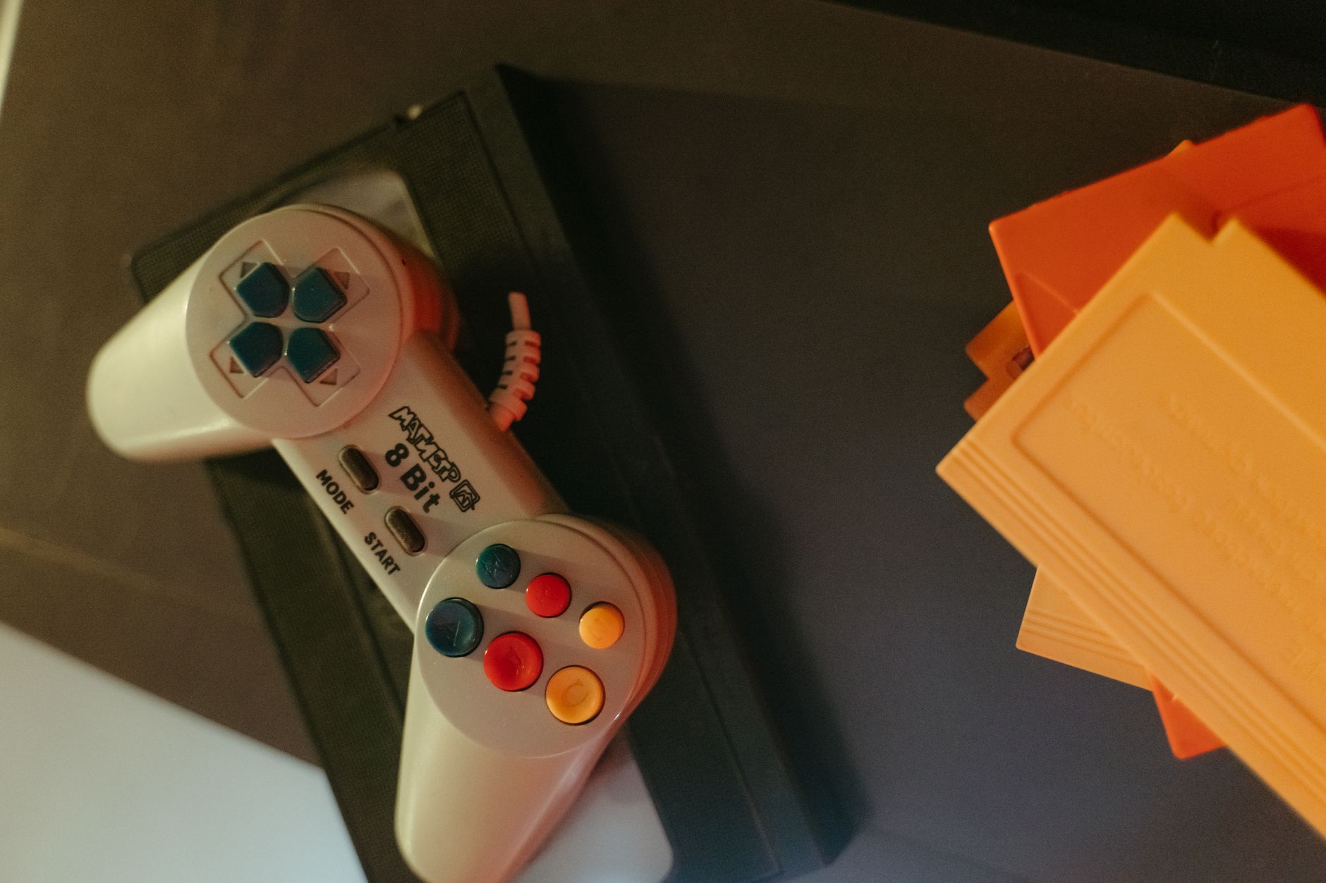 An older game console and controller on a desk, representing the revival of classic gaming entries like Ace Combat Zero