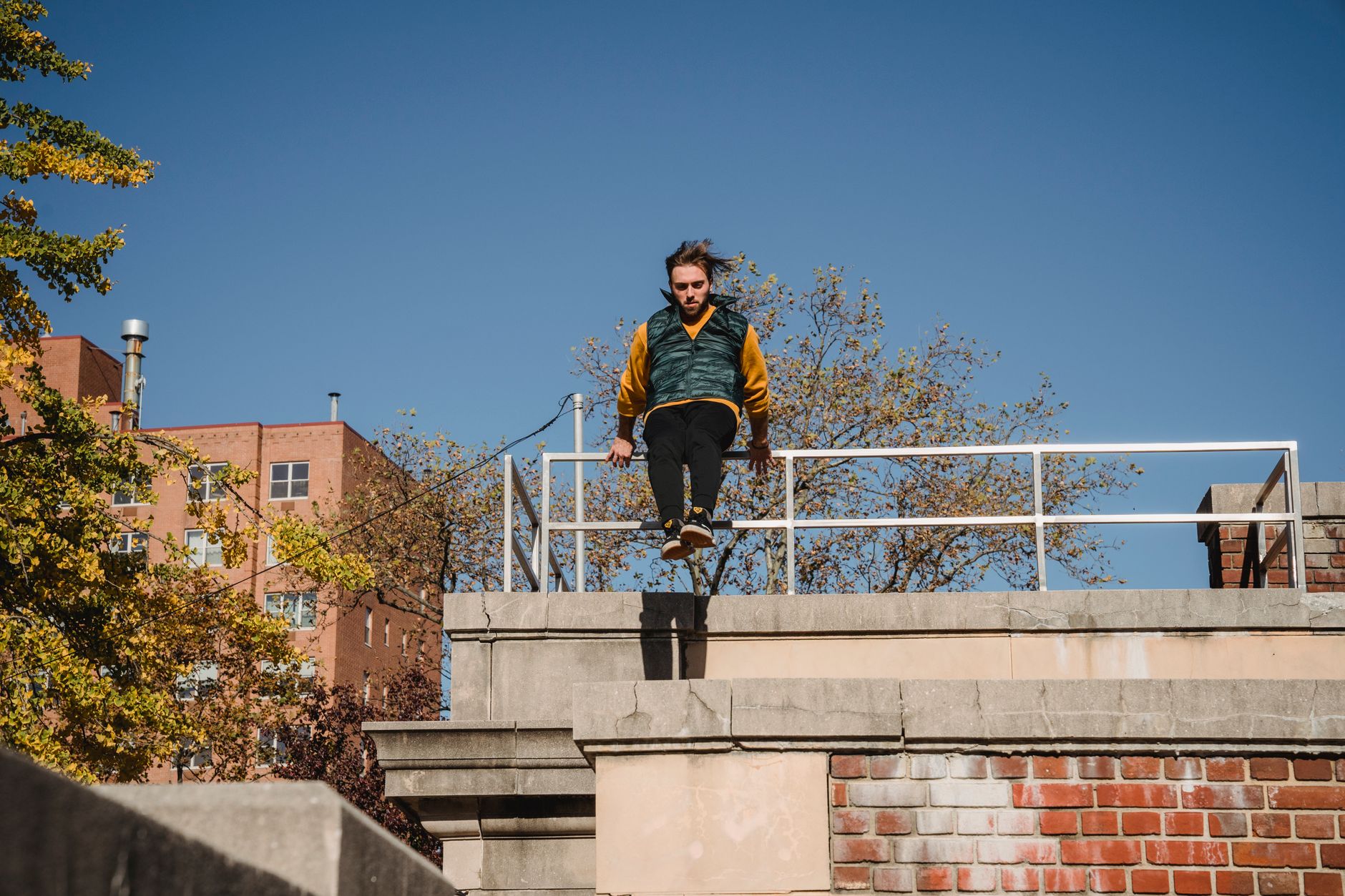 Person performing a parkour jump between rooftops at dusk