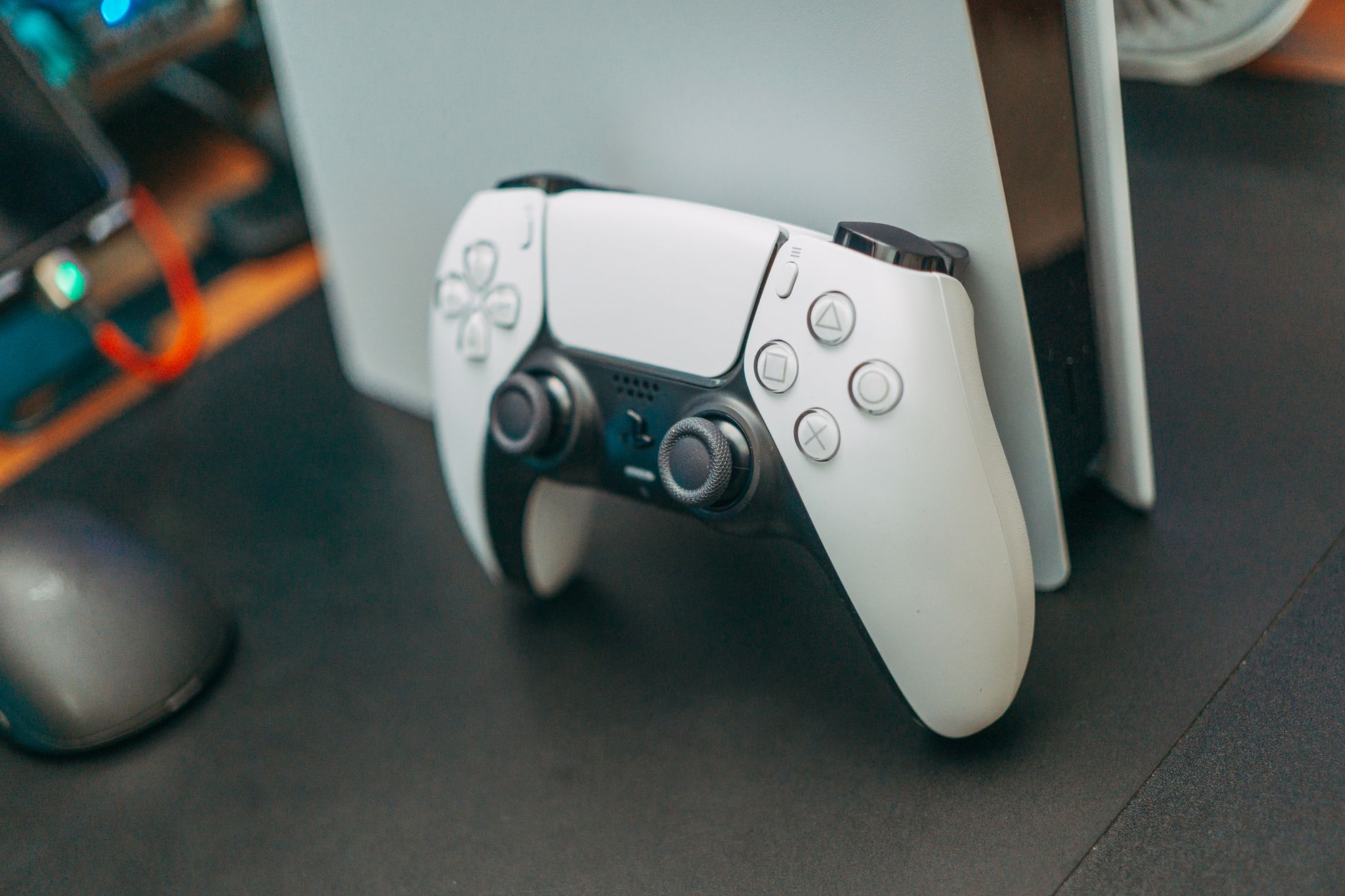 Gaming controller resting on a desk beside a monitor showing a game in progress