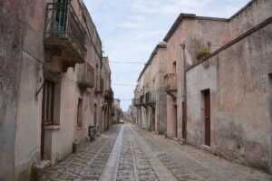 Sun-bleached Sicilian hillside village with stone architecture, evoking the setting of Mafia The Old Country