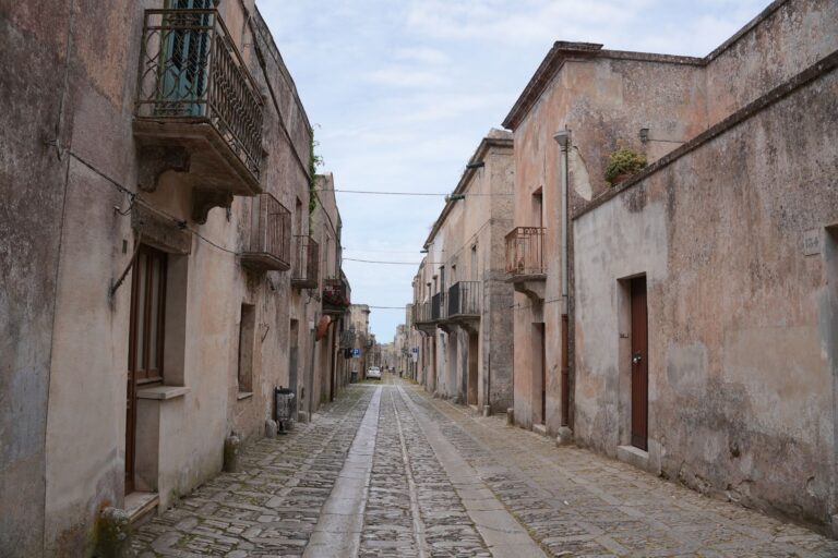 Sun-bleached Sicilian hillside village with stone architecture, evoking the setting of Mafia The Old Country
