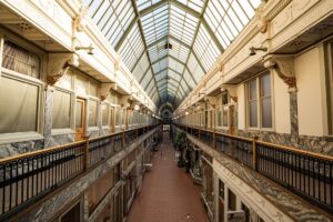 A dark, empty shopping mall corridor with dramatic lighting suggesting tension and abandonment