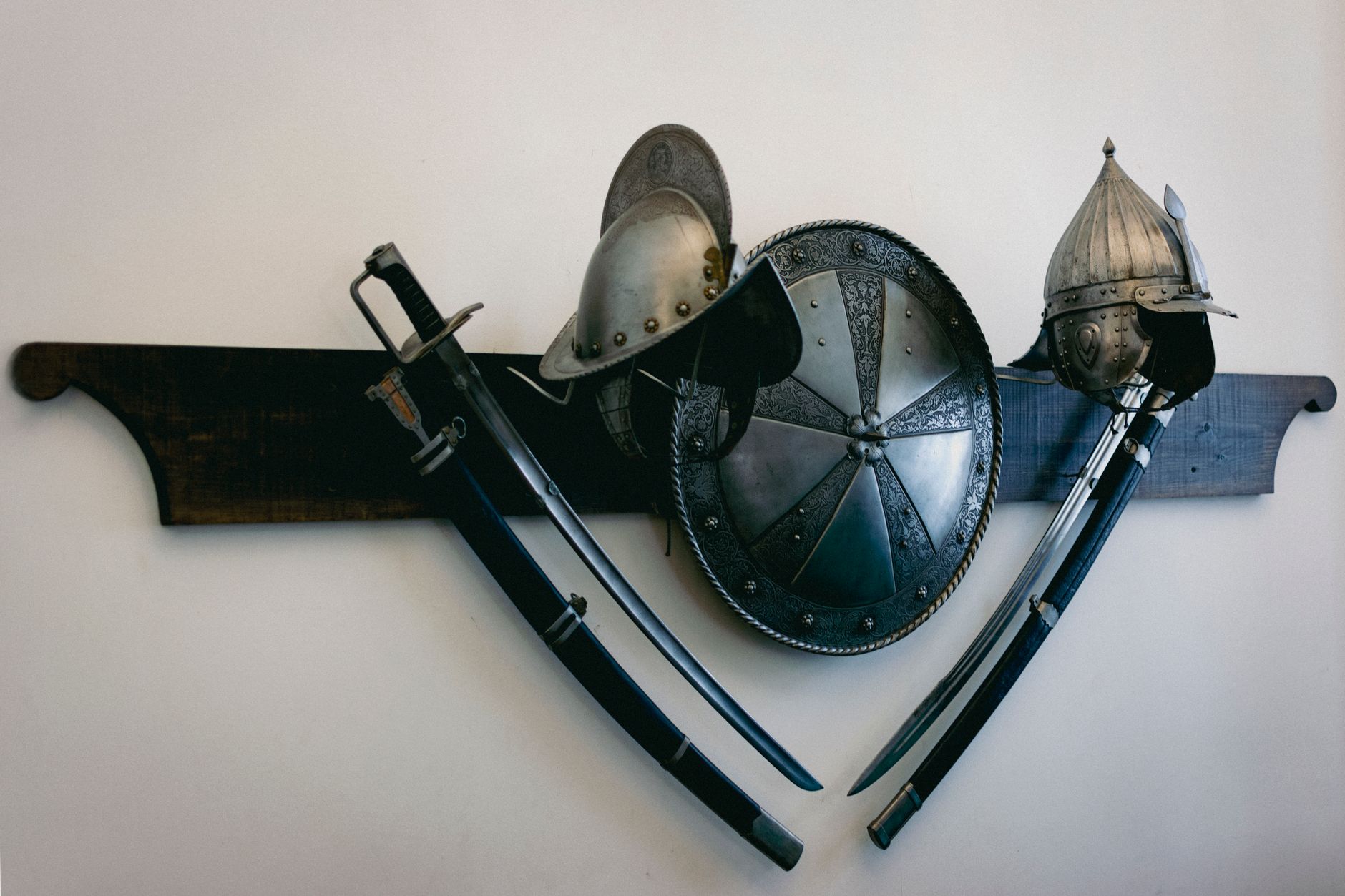 Collection of medieval swords and shields displayed against a stone wall